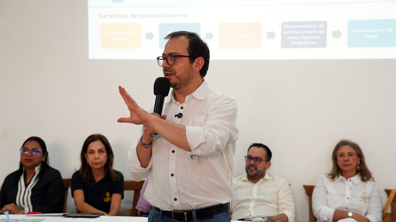 Un hombre presenta información a un grupo de personas sentadas, prestando atención a su discurso.